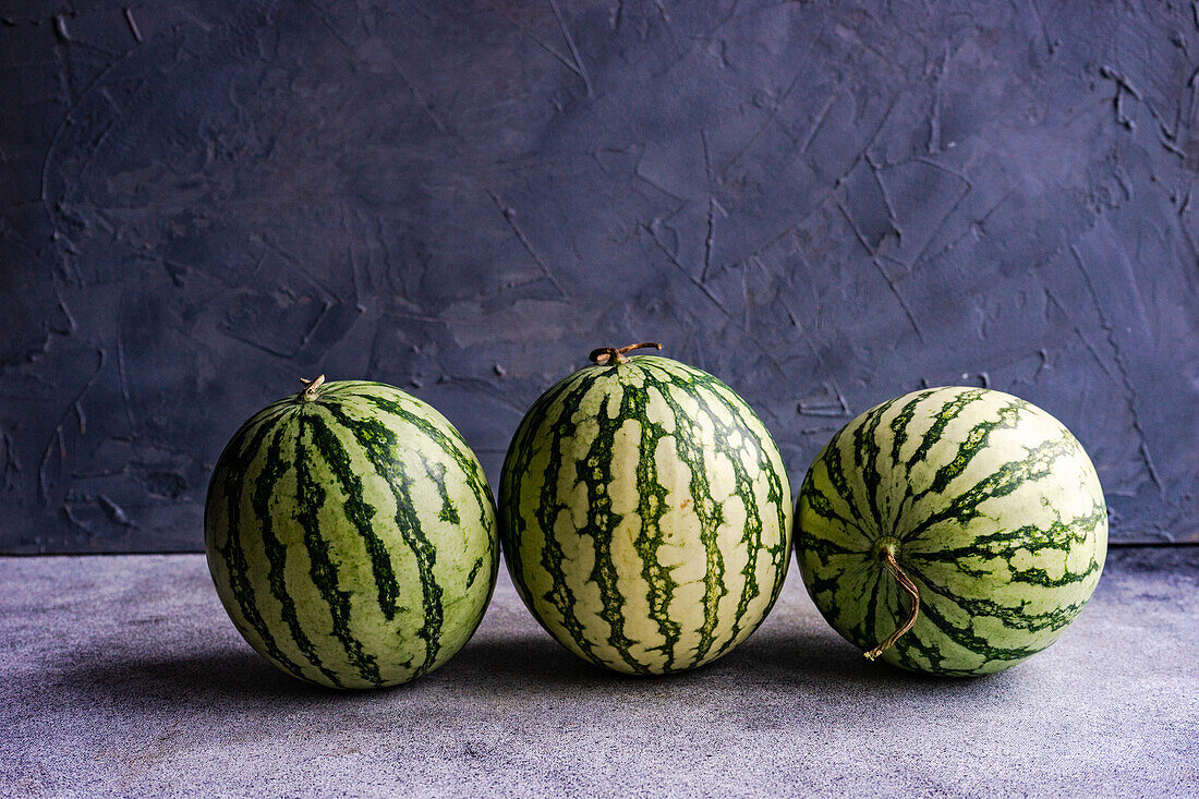 Stilleben Komposition von ganzen reifen gestreiften grünen Wassermelone auf Beton Hintergrund