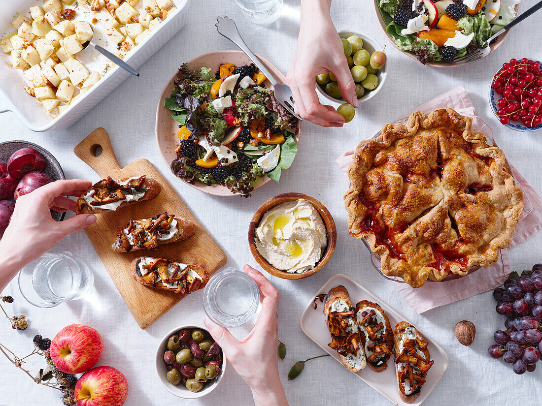 Vegetarisches Abendessen mit verschiedenen Snacks und Gerichten: Salatteller, Bruschetta, gebratenes Gemüse und ein Kuchen