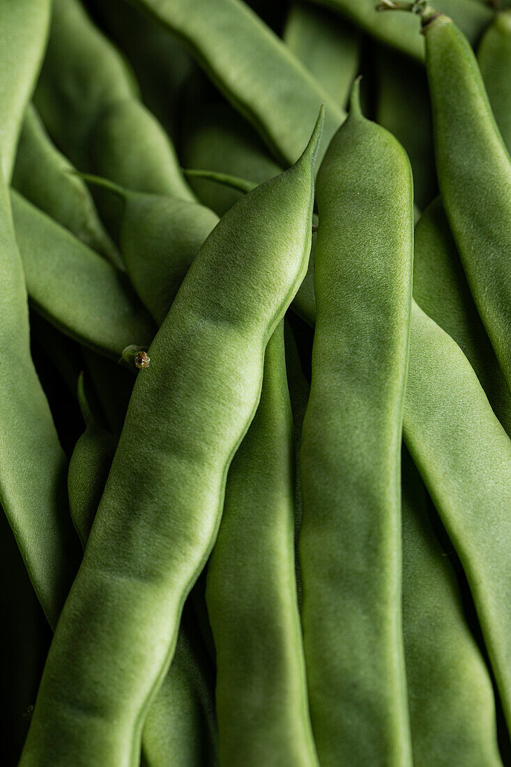 Vollbildansicht von oben eines Haufens frischer grüner Stangenbohnen, die aneinandergereiht sind