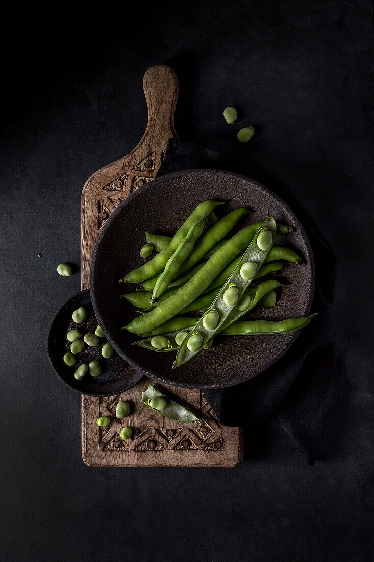 Top view of composition of two bowls with organic raw French beans and legumes on decorative cutting board