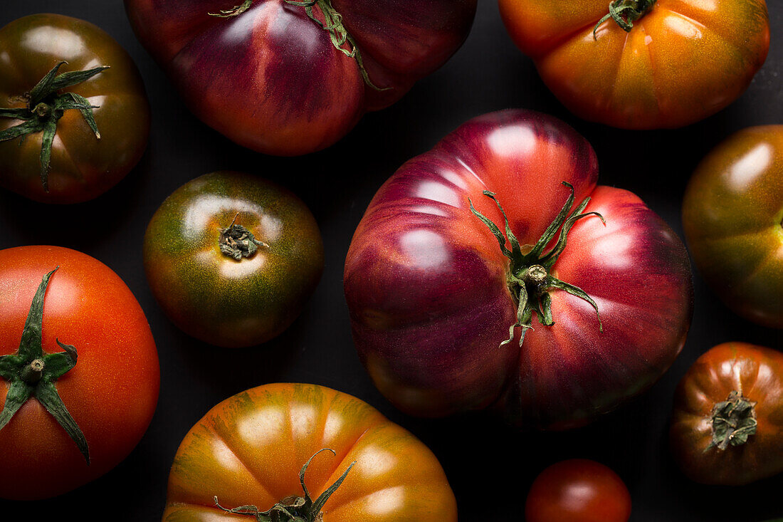 Von oben verschiedene frische Tomaten auf einem schwarzen Tisch