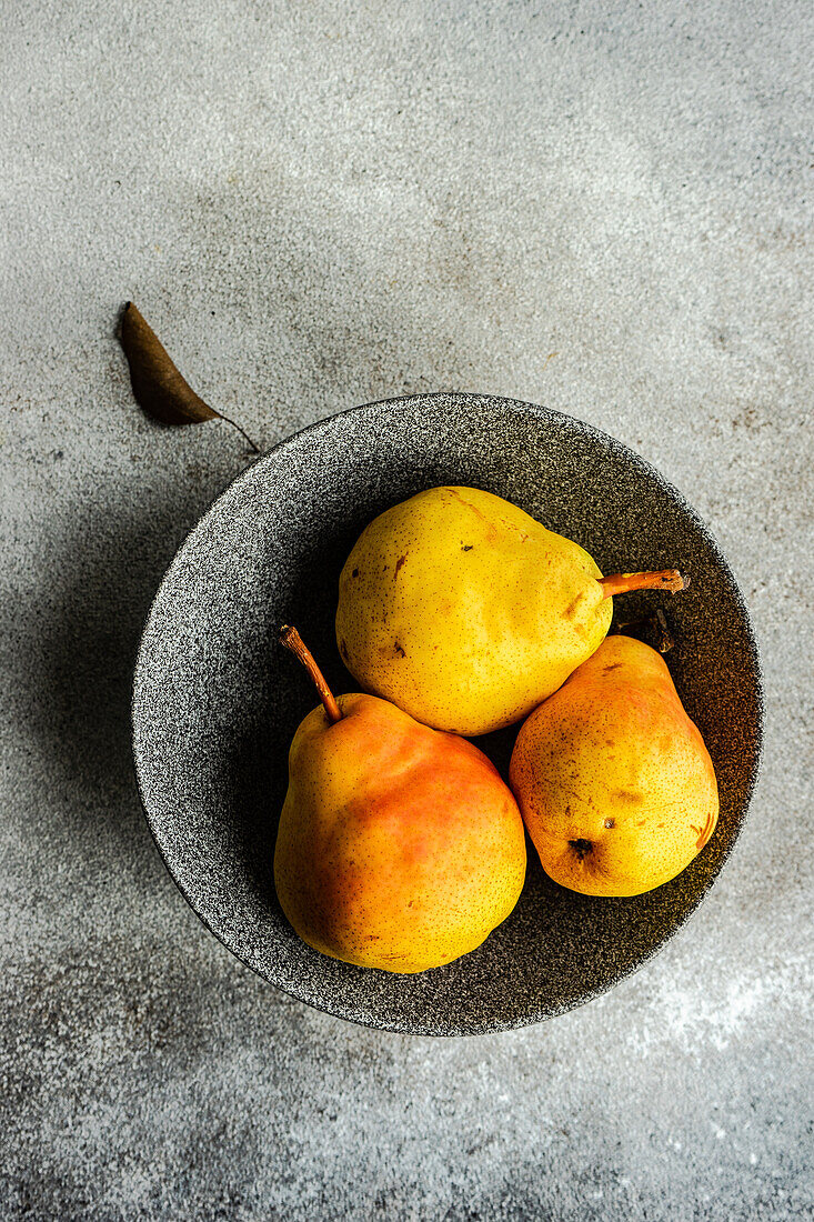 Von oben Keramikschale mit Bio-Birnen Obst auf Betonoberfläche