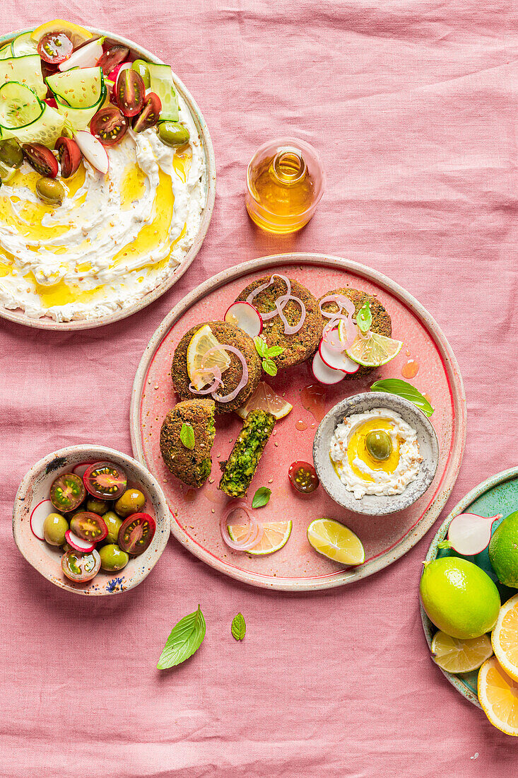 Top view of plate with delicious cream cheese and assorted vegetables placed on napkin near vegan fritters on pink background