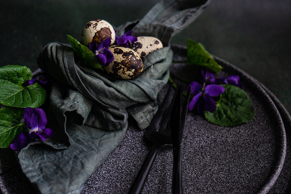 Spring table setting with wild blue viola flower on black plate set