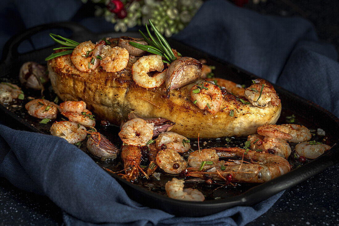 Schwarzes Tablett von oben mit appetitlichem gebackenem Schwertfisch, serviert mit Garnelen und konfitiertem Knoblauch