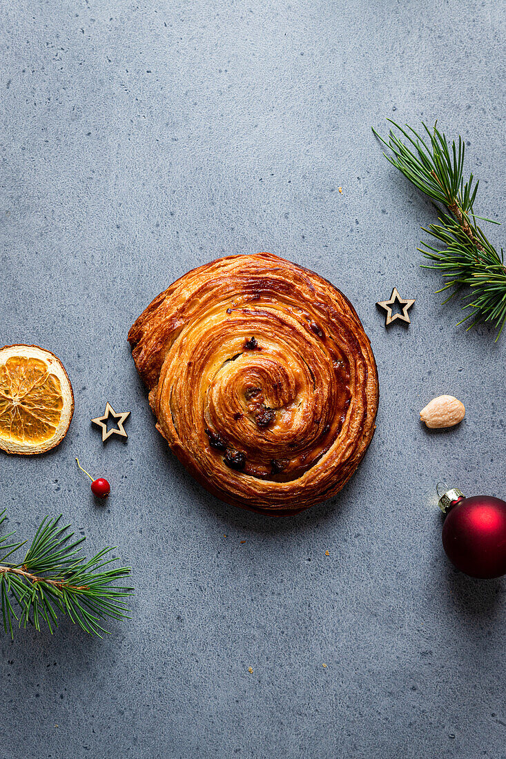 Draufsicht auf leckeren hausgemachten Schneckenkuchen auf einem grauen Brett mit Weihnachtsdekoration drum herum