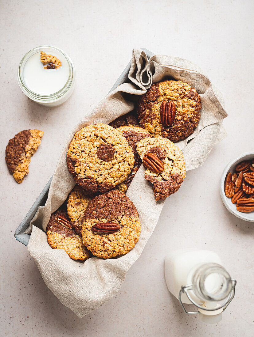 Top view of sweet cookies with walnuts and glass on milk placed on white table