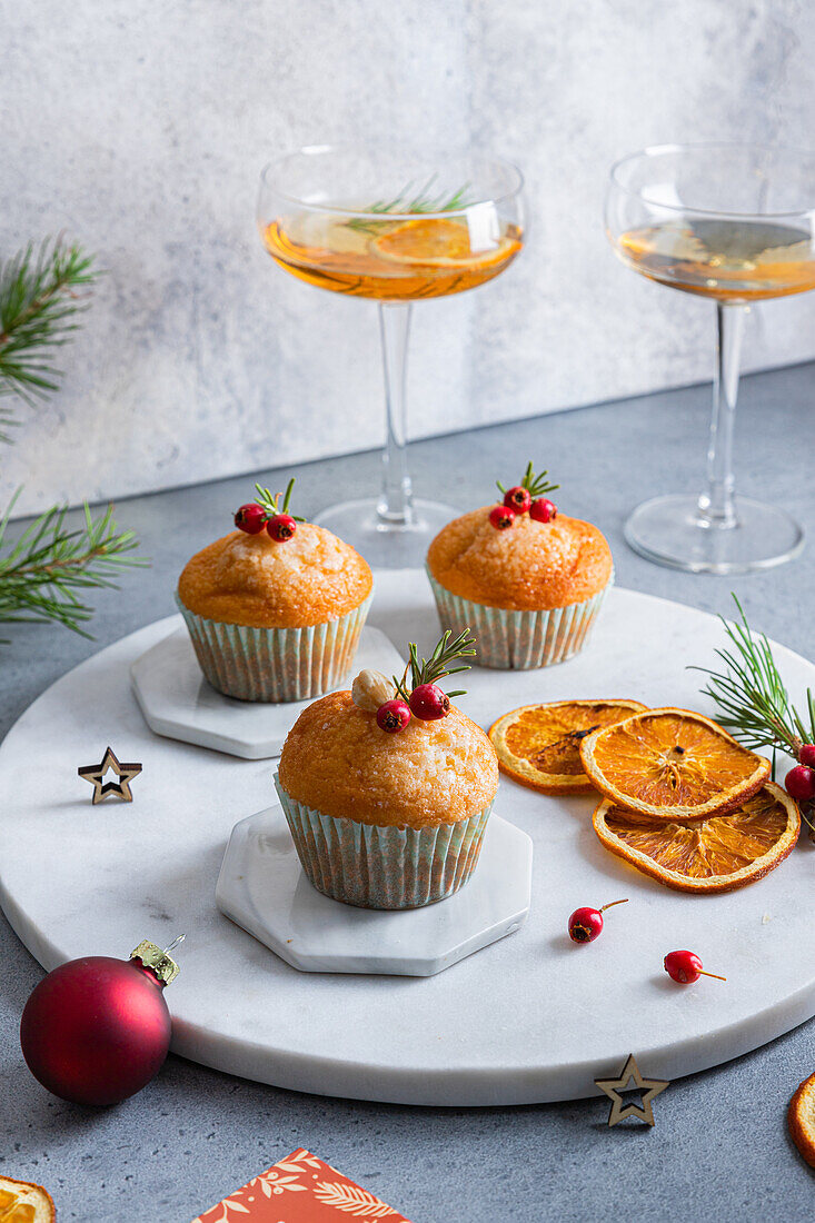 From above composition of appetizing christmas cupcakes with dried oranges and berries on white marble stand