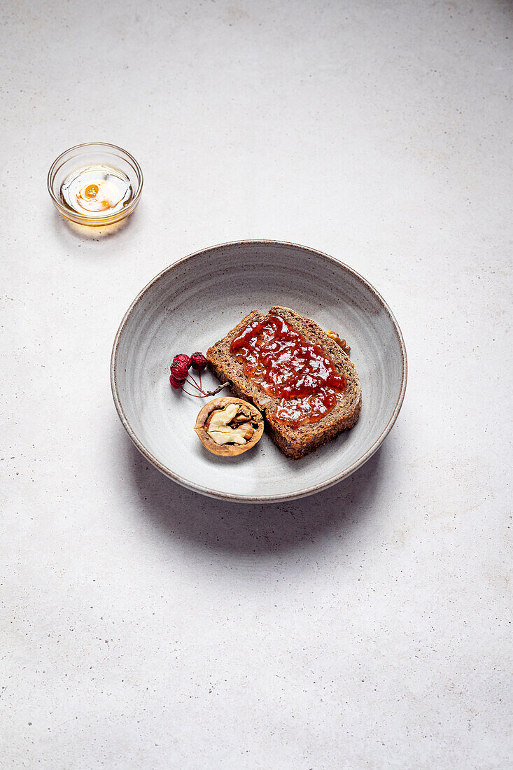 Top view of rye bread with jam near half of walnut composed with honey