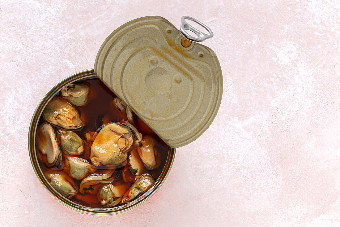 Top view of appetizing mussels in a open can with sauce on table