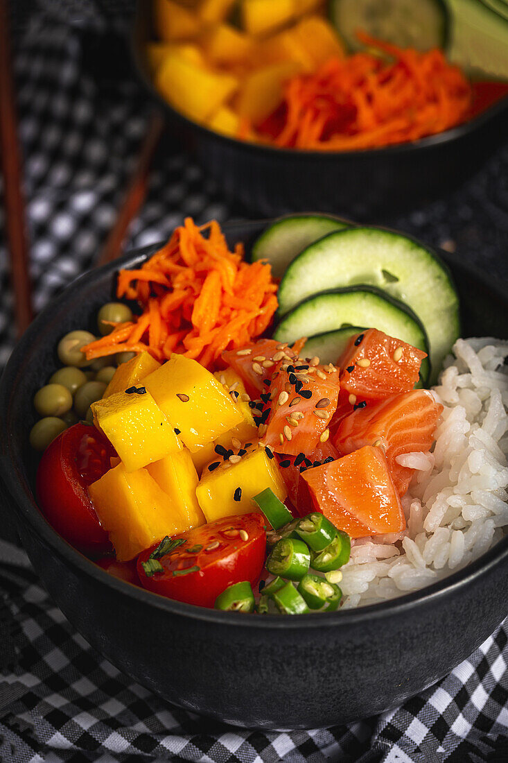 Asiatischer Poke mit Lachs und Reis mit verschiedenen Gemüsesorten, serviert in einer Schüssel auf einem Tisch mit Stäbchen in einem Restaurant