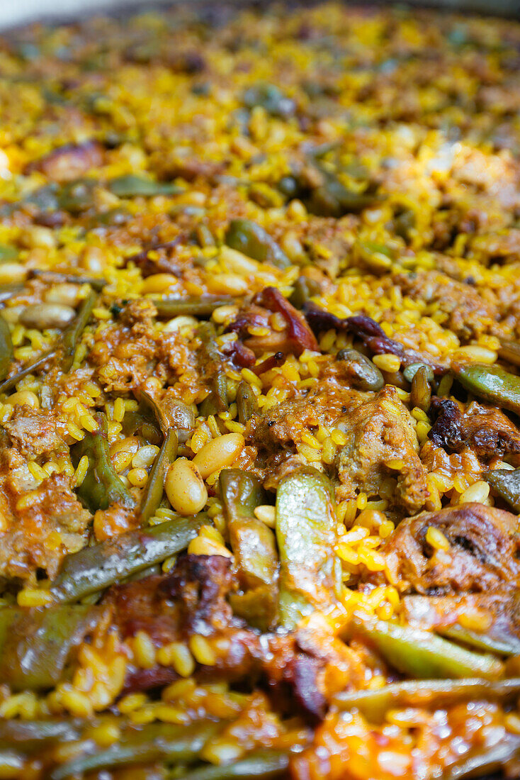 Nahaufnahme einer köstlichen traditionellen spanischen Paella mit Huhn und Bohnen im Garten