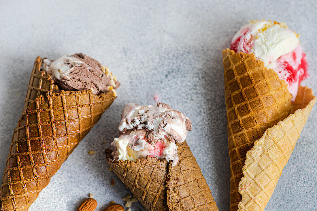 From above waffle cones with cherry and chocolate ice cream on concrete background