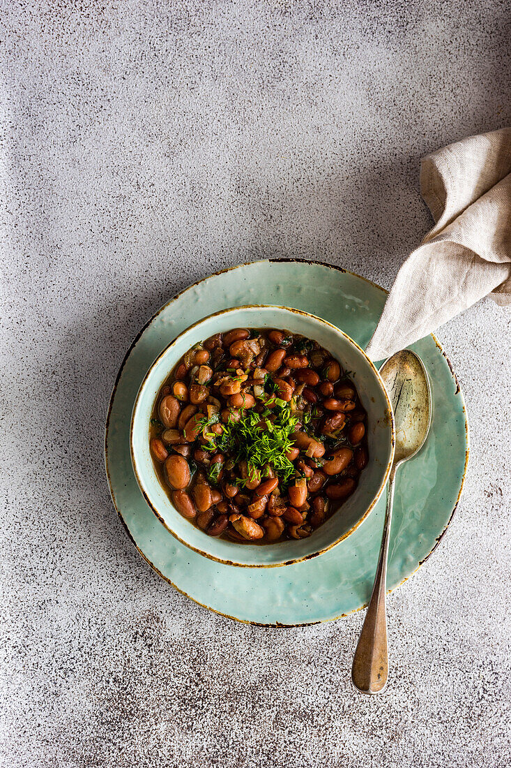 Vegetarische Bohnensuppe, serviert in einer Keramikschale mit Zwiebel und Korianderkraut