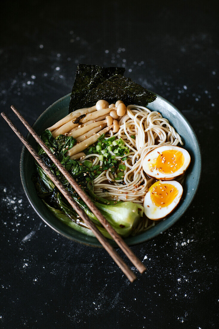 Top view of ceramic bowl with delicious ramen and chopsticks placed on table