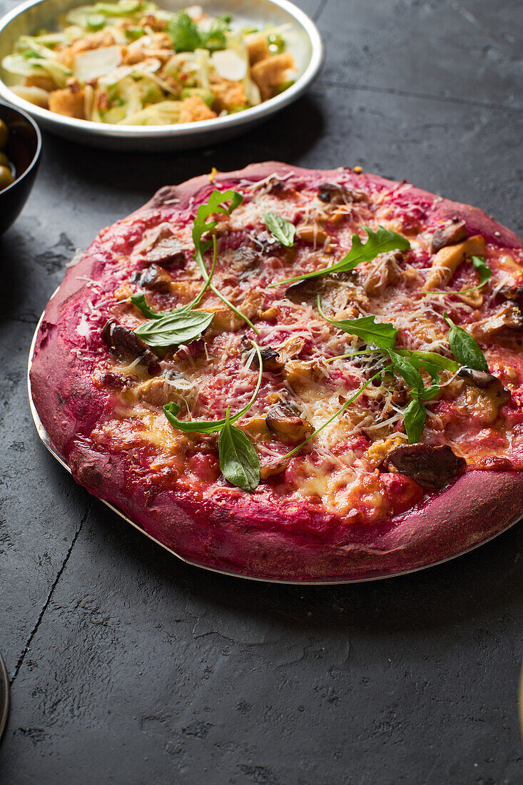 Purple colored rustic pizza with beetroot and vegetarian topping. Top view healthy food recipe