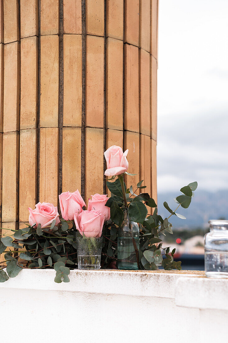 Pink roses inside glass vases placed on terrace outdoors
