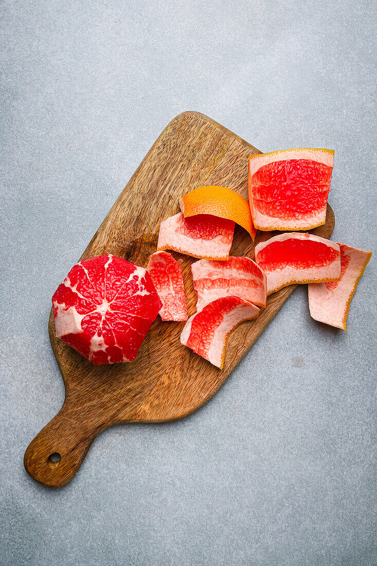 Top view of delicious peeled red orange placed near peel on wooden cutting board