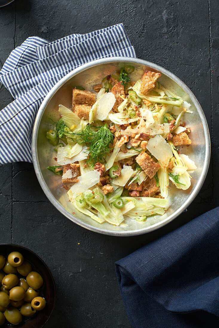 Top view fennel salad with parmesan cheese, walnuts and croutons on grey background