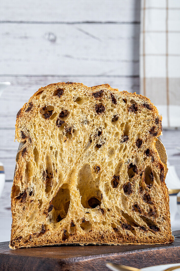 Köstliche Hälfte eines hausgemachten Panettone auf einem Holztisch vor hellem Hintergrund