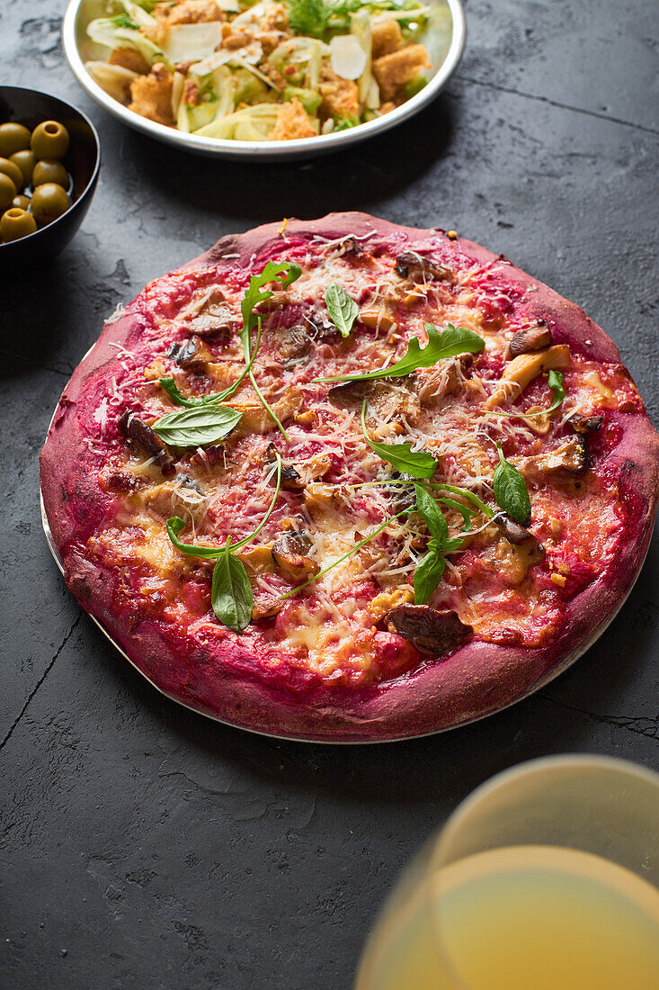 Lila gefärbte rustikale Pizza mit Roter Bete und vegetarischem Belag. Ansicht von oben gesundes Essen Rezept