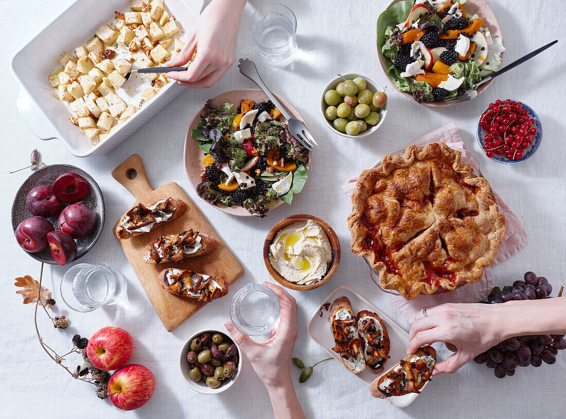 Vegetarian dinner with various snacks and dishes: salad plates, bruschetta, roasted vegetables and a pie