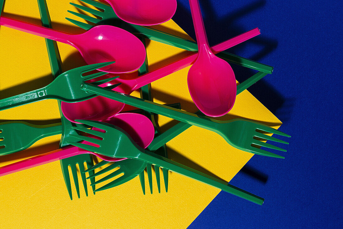 Overhead view of bright colorful eco friendly cutlery near yellow carton sheet