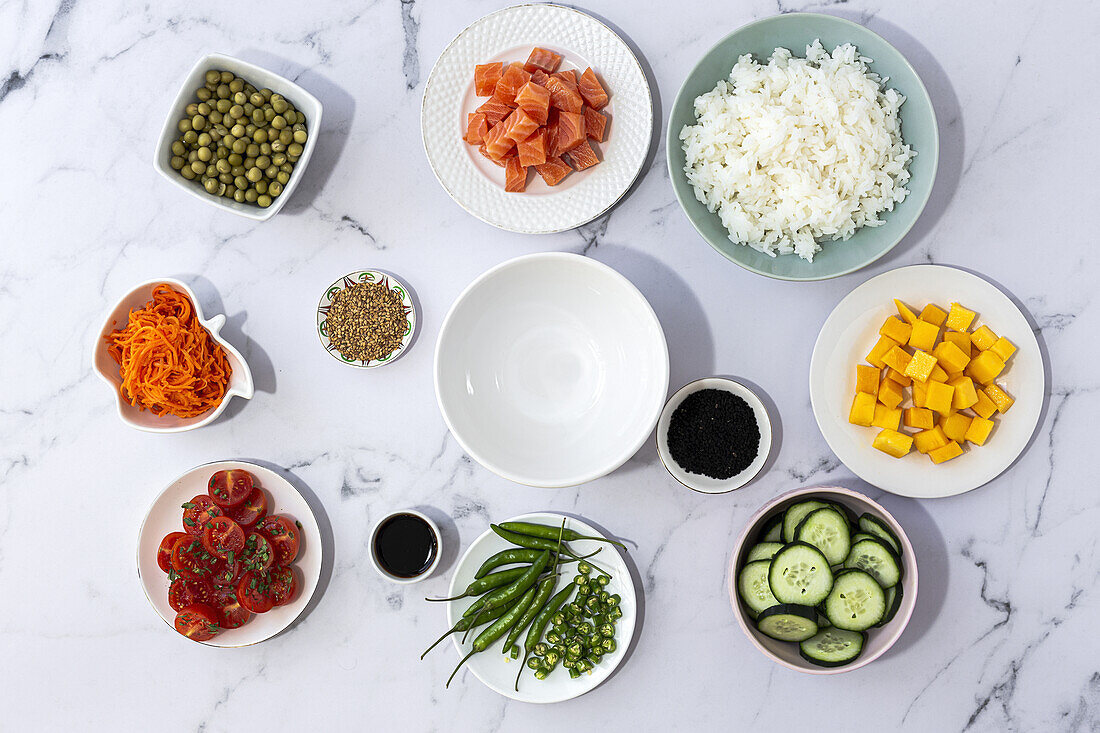Top view of assorted fresh ingredients for traditional oriental poke preparation placed on marble tabletop