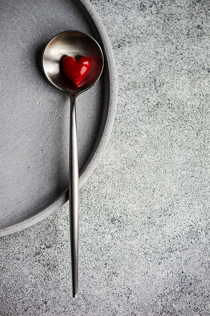 Valentinstagsservice mit rotem Glasherz auf Betontisch