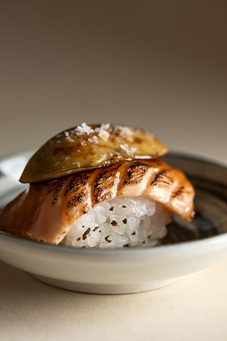 Tasty Japanese Horwegian nigiri sushi with smoked salmon and flambeed foie gras served on plate in restaurant