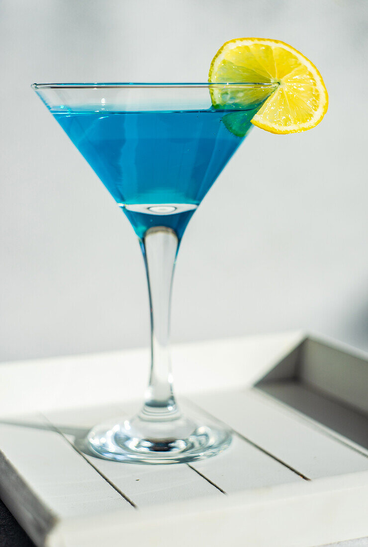 Glass of blue kamikaze drink on stone table in modern style