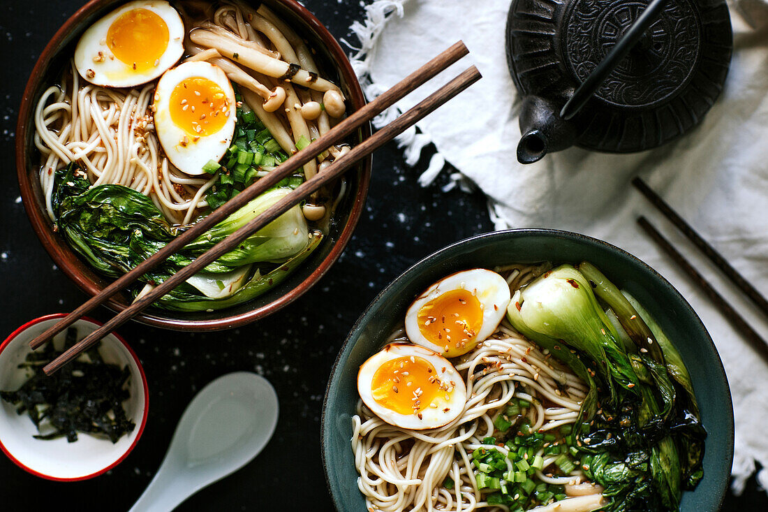 Top view of ceramic bowls with delicious ramen and chopsticks placed on table