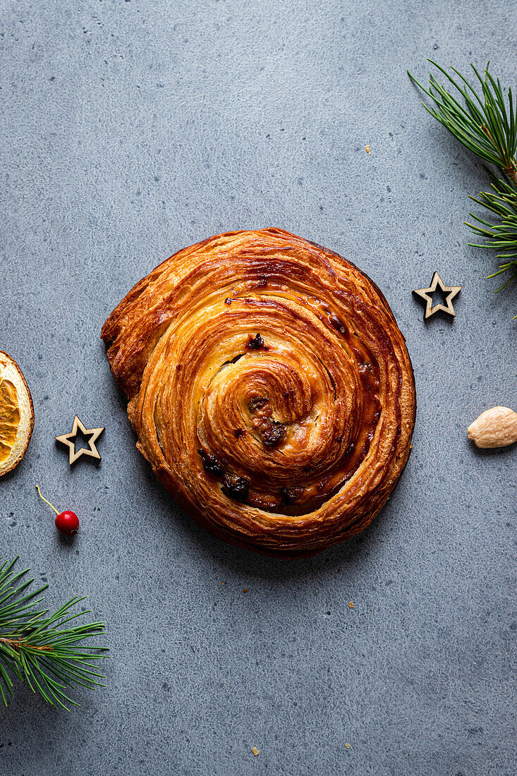 Top view of delicious homemade baked snail pastry placed on grey board with Christmas decoration around