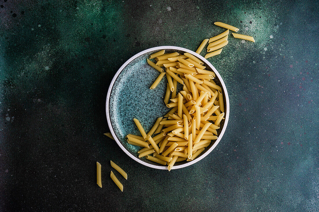 From above uncooked raw penne pasta on the plate