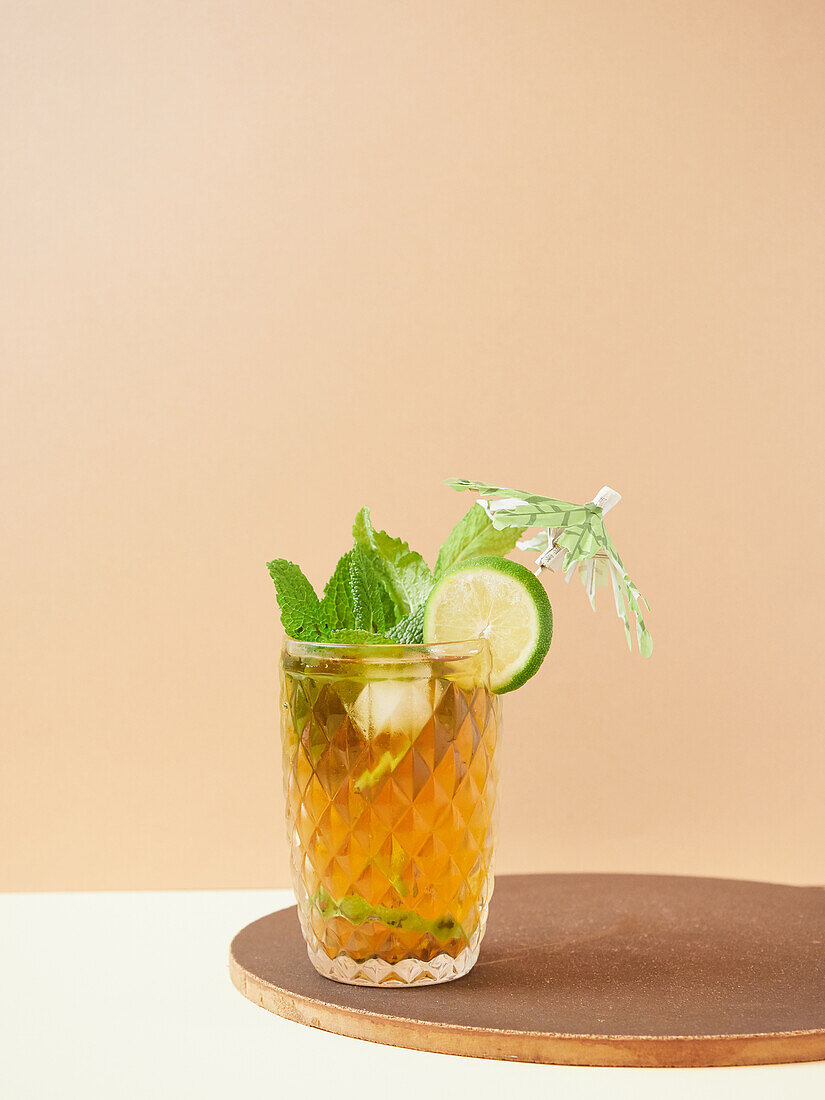 Glas köstlicher alkoholfreier Cocktail mit Limetten- und Zitronenscheiben, dekoriert mit Minzblättern auf einem Holzbrett