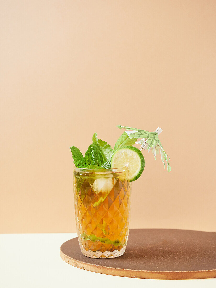 Glass of delicious nonalcoholic cocktail with lime and lemon slices decorated by mint leaves on wooden board