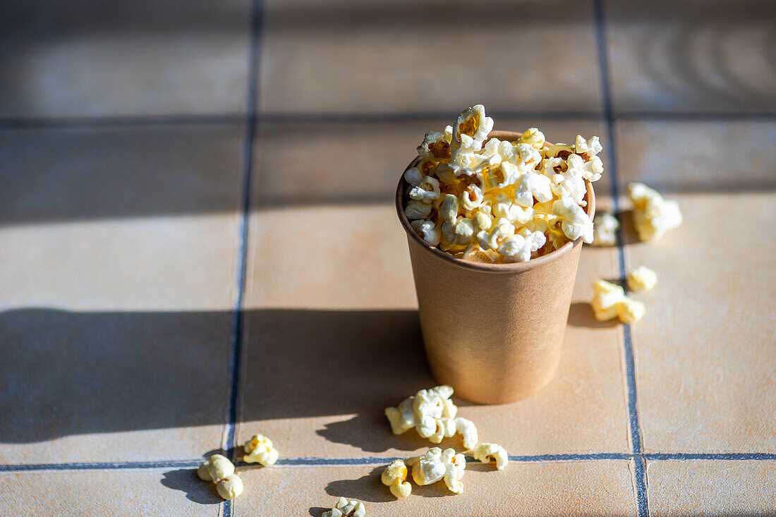 Paper cup with popcorn snack on the tiled table