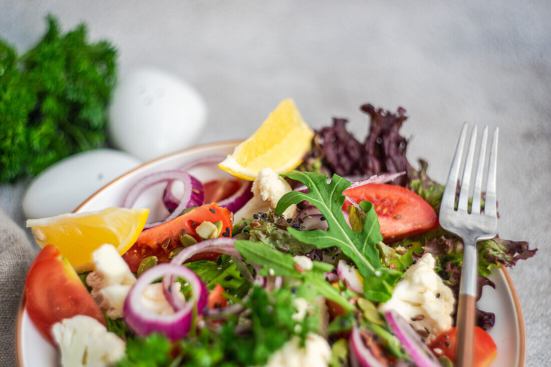 Organic vegetable salad with seasonal vegetables and herb mix with seeds and lemon in a bowl