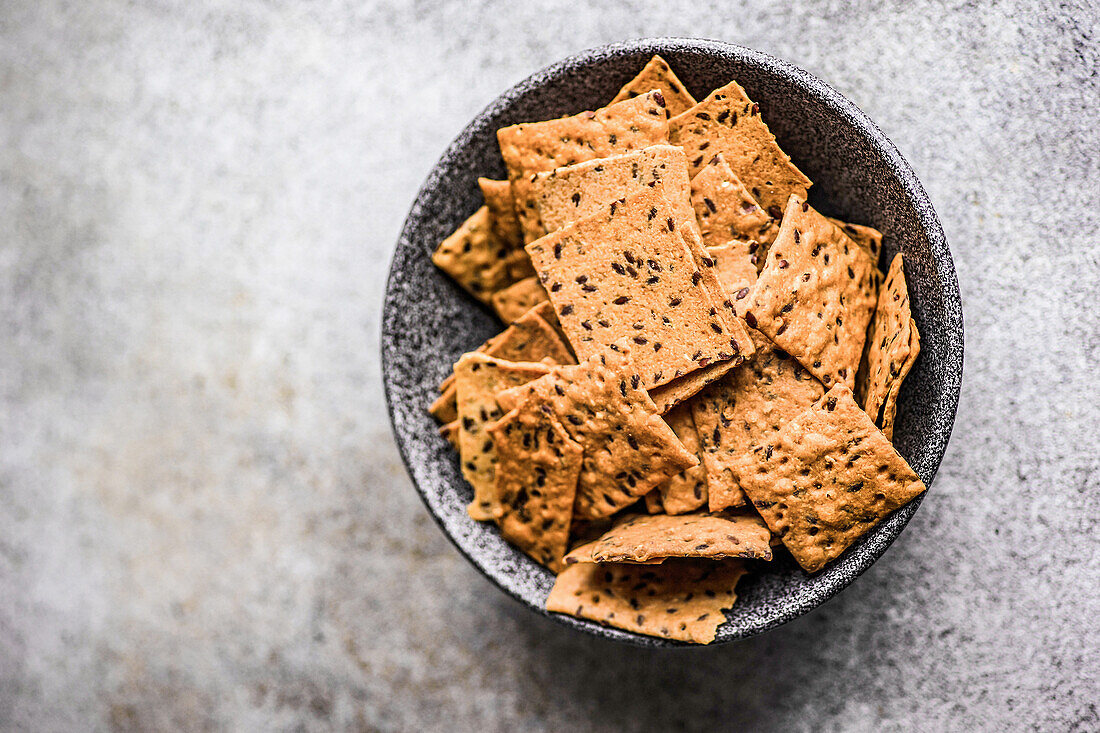 Bowl of healthy flax and sesame seeds chips on the concrete background