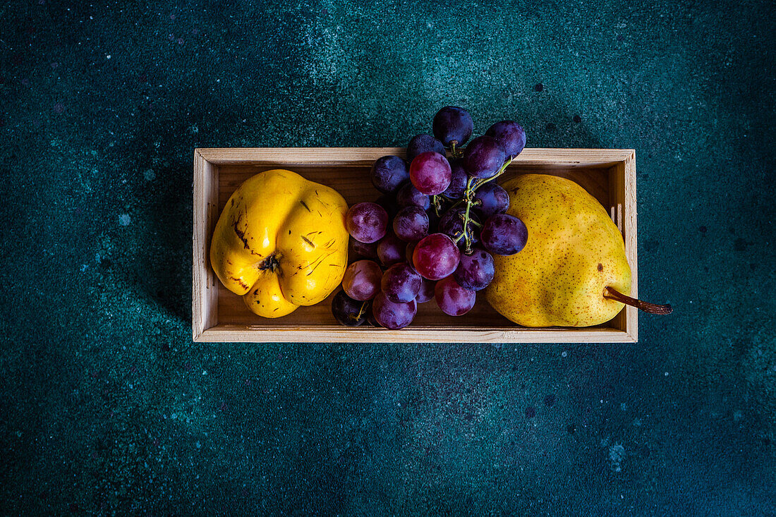 From above box with ripe organic grape, quince and pear on the concrete table