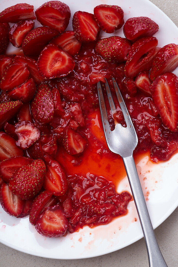 Sugar-coated sliced strawberries on a plate. Cooking dessert or jam