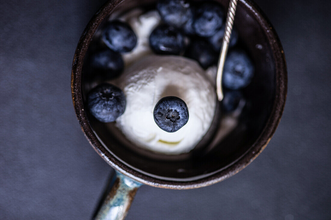 From above bowl full of delicious ripe blueberries placed on black background