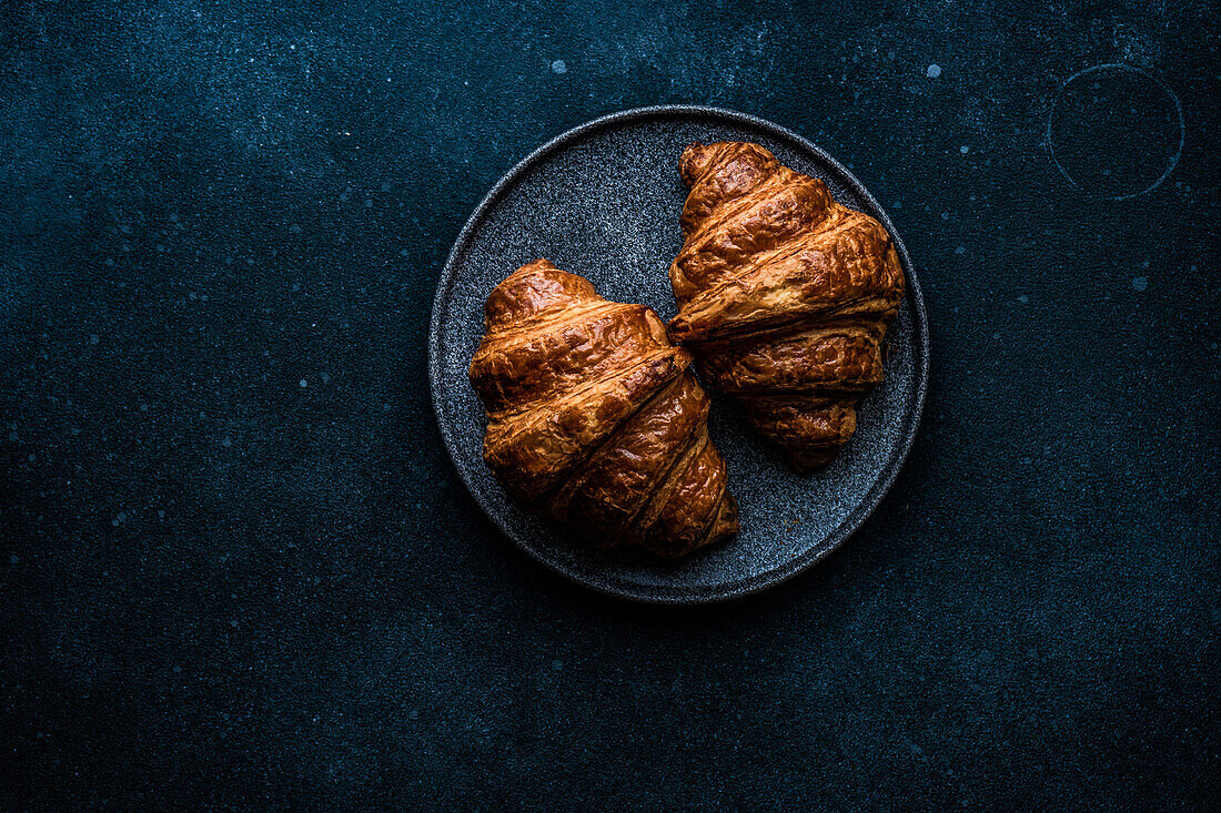 From above fresh baked croissant with jam on the concrete blue table