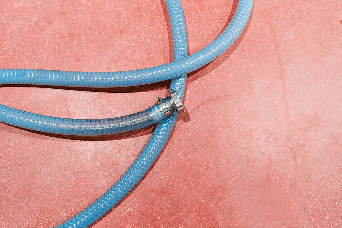 Top view of plastic ribbed hose with metallic connector and shiny surface in industrial workspace
