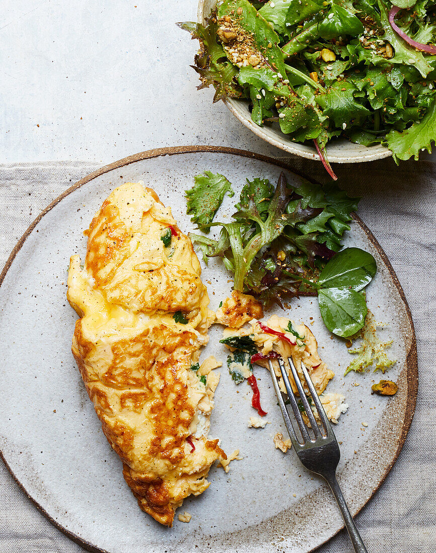 Top view of appetizing vegetarian salad with green herbs and omelette on plate served with fork