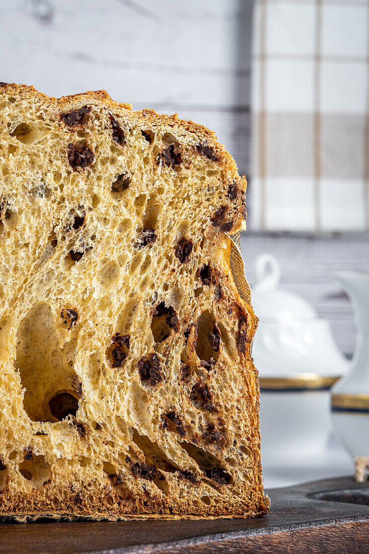 Close up view of delicious half of homemade panettone placed on wooden table against light background