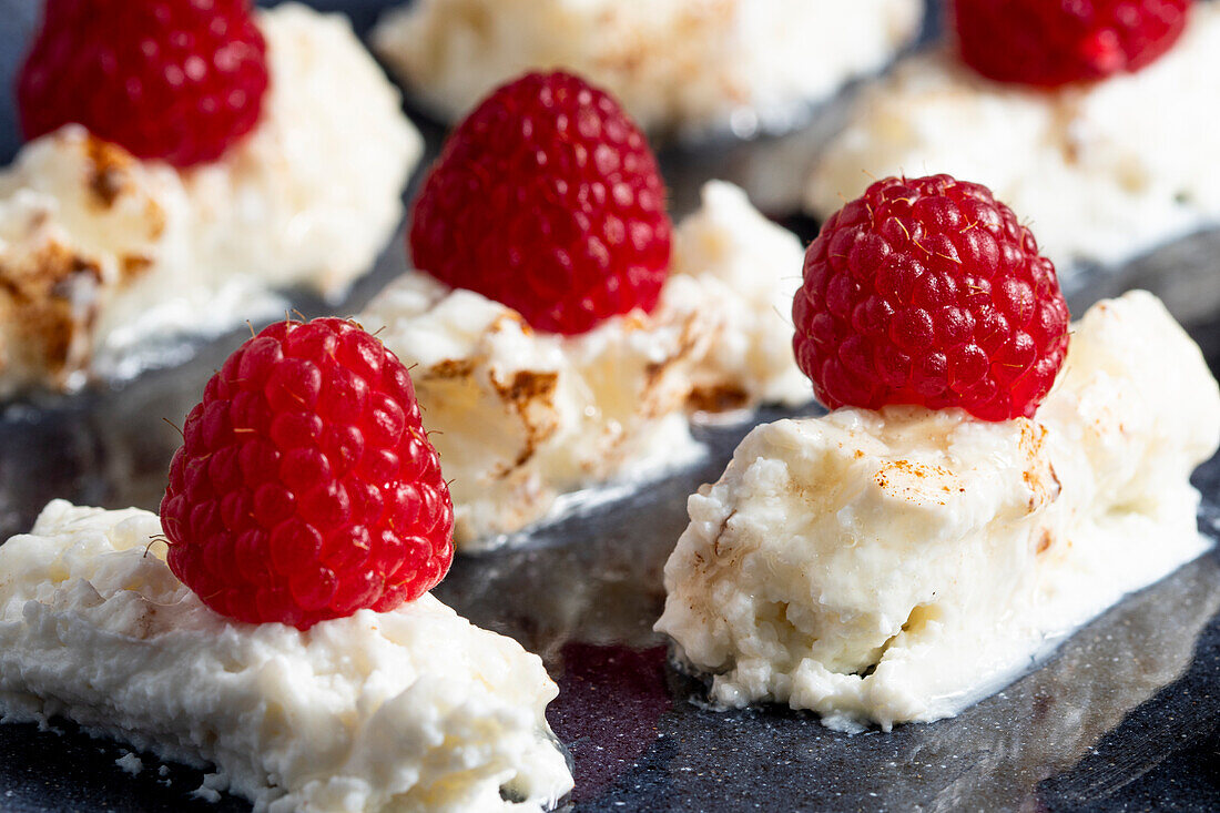 Appetizing delicious creamy dessert with fresh ripe raspberries placed on plate in cafe
