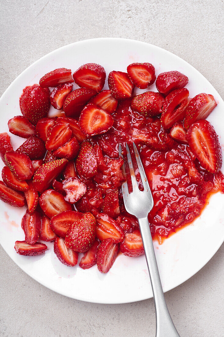 In Scheiben geschnittene Erdbeeren mit Zucker überzogen auf einem Teller. Kochen von Dessert oder Marmelade