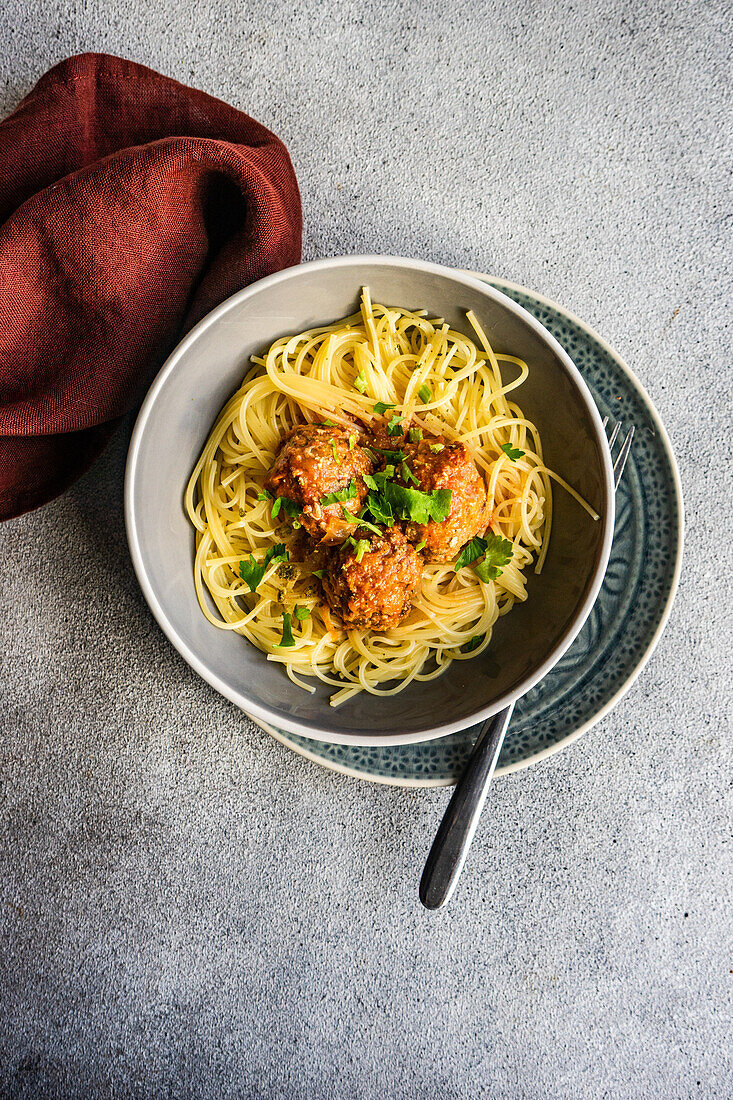 From above bowl with pasta and meatballs on concrete table background