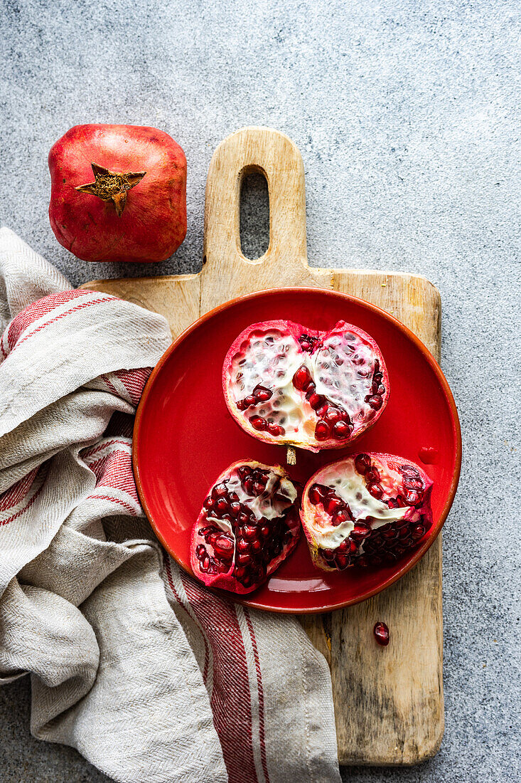 Organic ripe pomegranate fruit on red ceramic plate on stone background